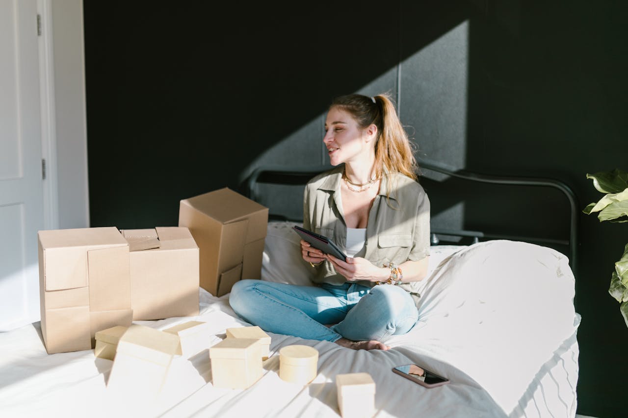 A Woman in Bed with Brown Boxes while Holding a Tablet